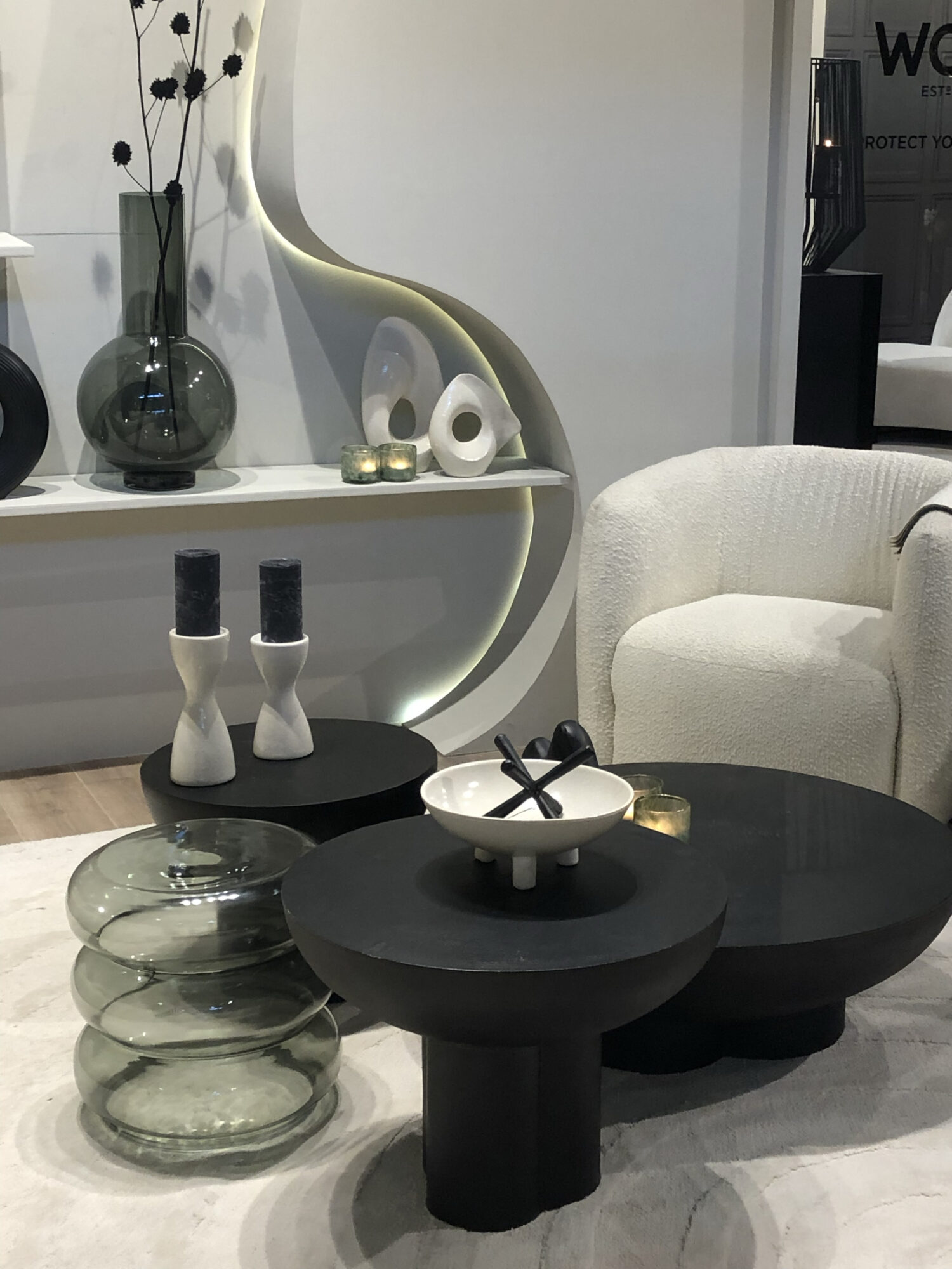 black nesting table with white armchair in background