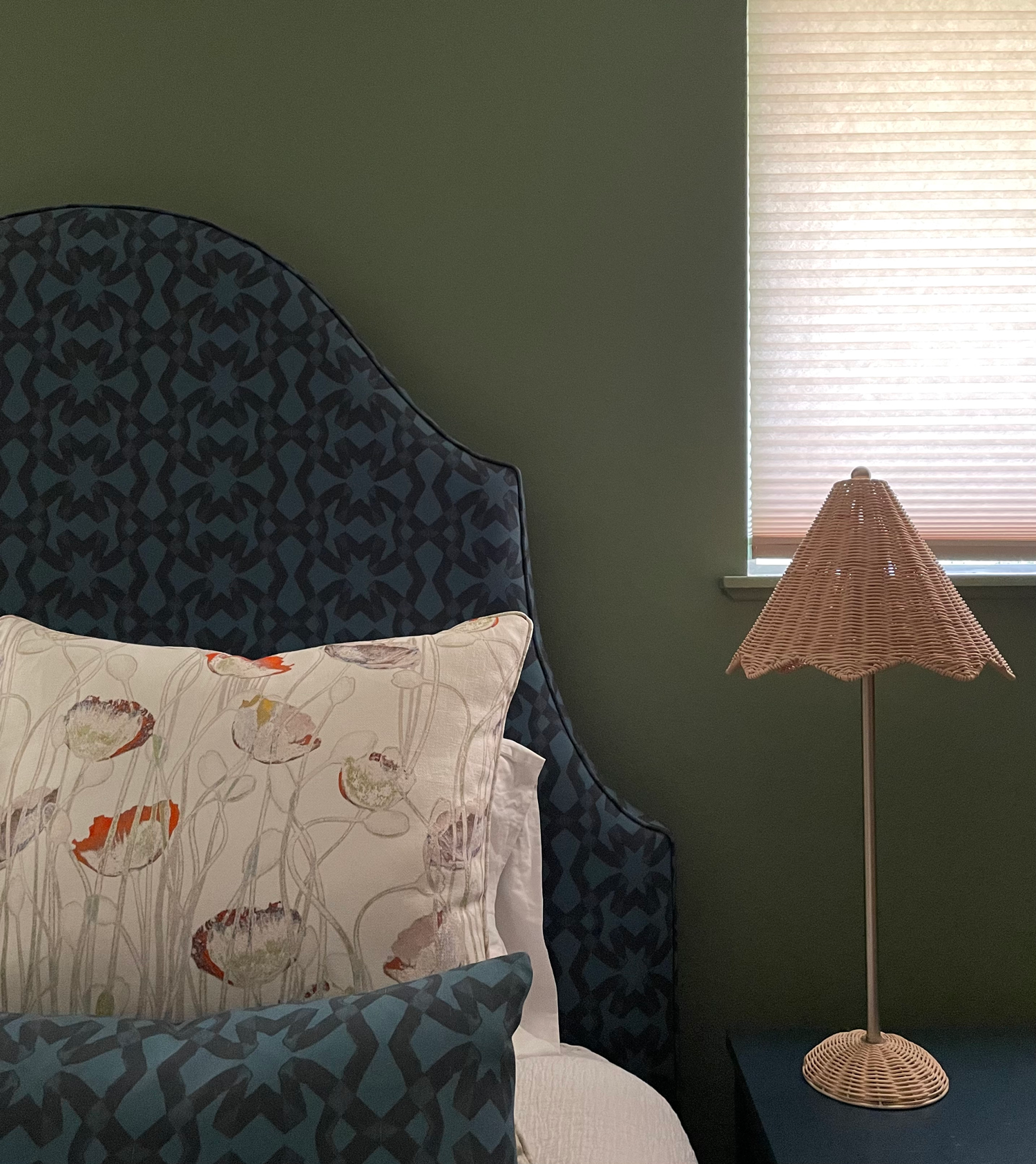 green bedroom with bed with blue headboard and rattan lamp as a 2024 paint color trend
