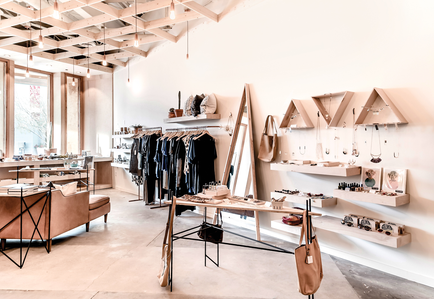 Boutique with light wood ceilings and wood shelves displaying jewelry, clothes and other accessories.