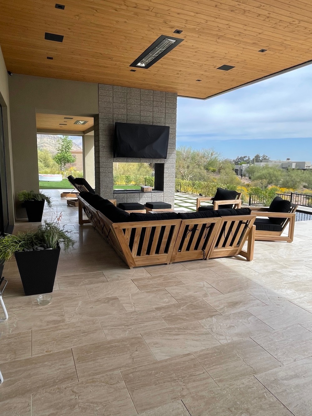 Teak outdoor sectional seating with dark cushions by Willow Creek under a covered patio, perfect for entertaining, in Los Angeles, California.