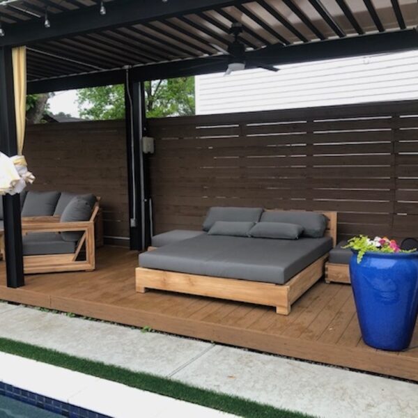 Teak outdoor chaise daybed with dark grey cushions in an outdoor cabana by Willow Creek Designs in California