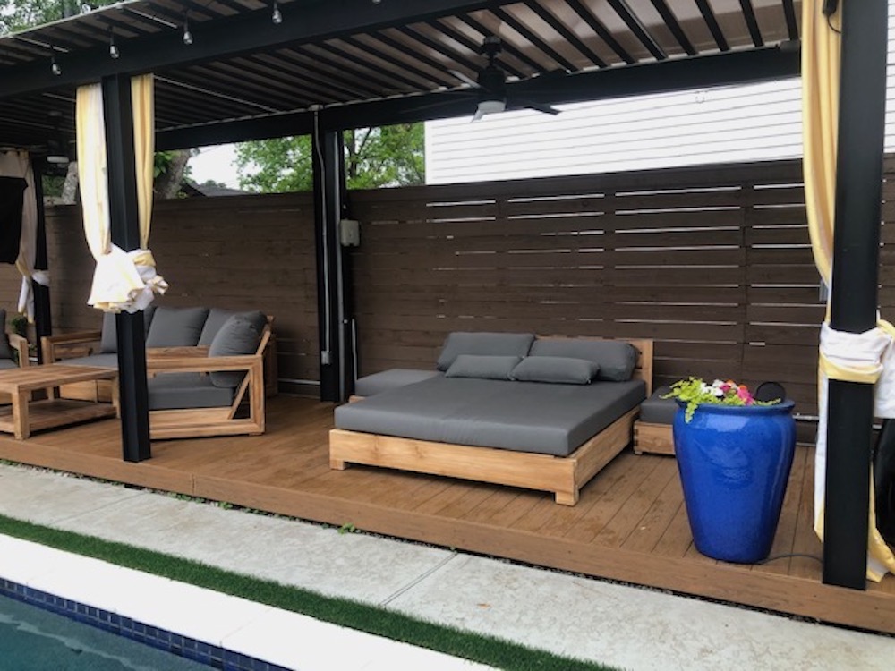 Teak outdoor chaise daybed with dark grey cushions in an outdoor cabana by Willow Creek Designs in California