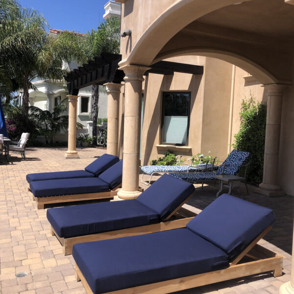 Teak outdoor chaise lounge chairs with blue cushions next to pool by Willow Creek Designs in California