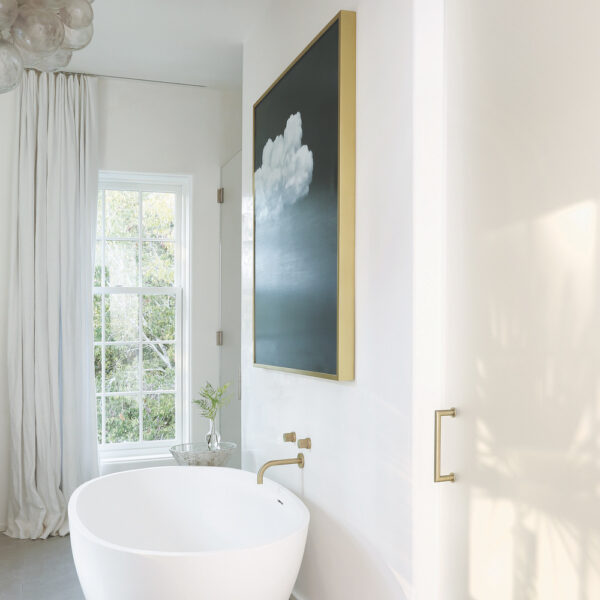 Paris Grey Limestone by Francois & Co in all white bathroom with white stand alone tub, gold fixtures, bubble lighting and bold artwork