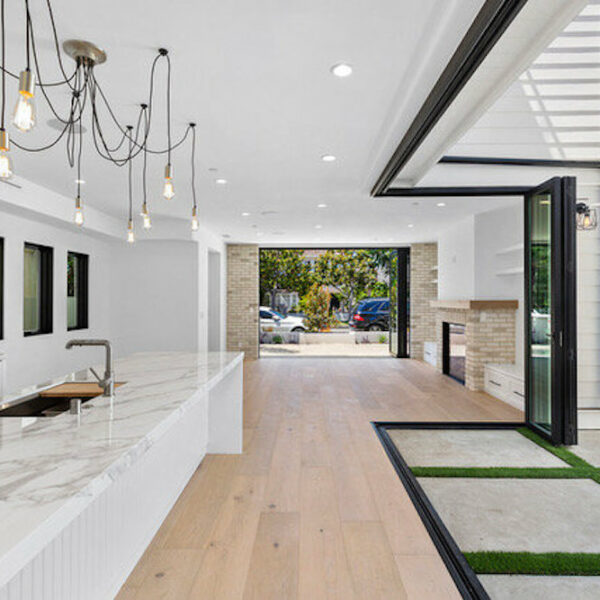All white modern kitchen with marble countertops, pendant lighting and floor to ceiling doors that provide an indoor-outdoor living space.