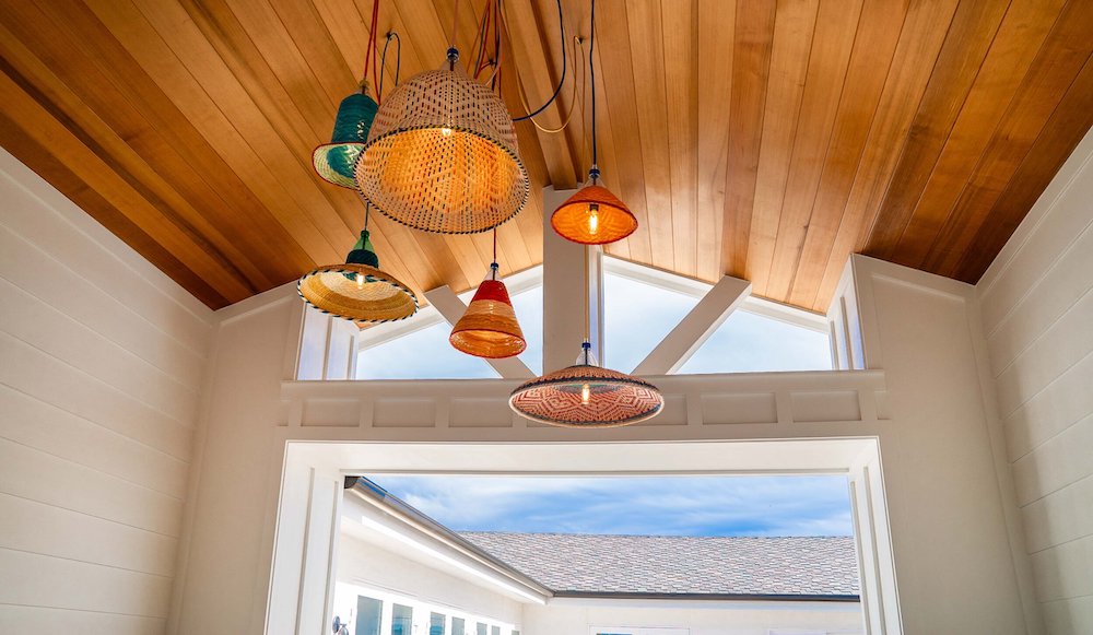 A vibrant living room with a wooden ceiling adorned with colorful hanging light fixtures that cast a warm and inviting glow, creating a striking contrast against the rich wood grain.