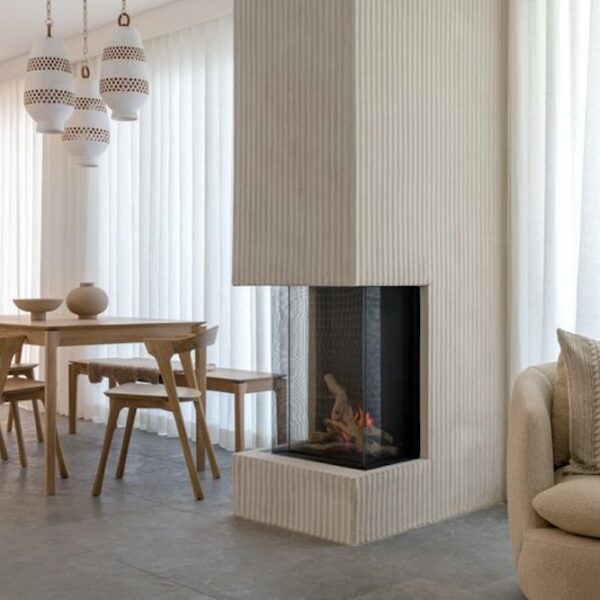 A mid-century modern dining room with a chic fireplace as the focal point. The room is furnished with iconic mid-century modern pieces in neutral tones, complemented by warm, ambient lighting.