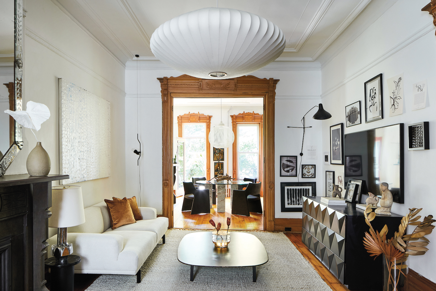 Over-scale fluted white chandelier in living room with crown molding and a black-and-white palette by Meghan Grehl