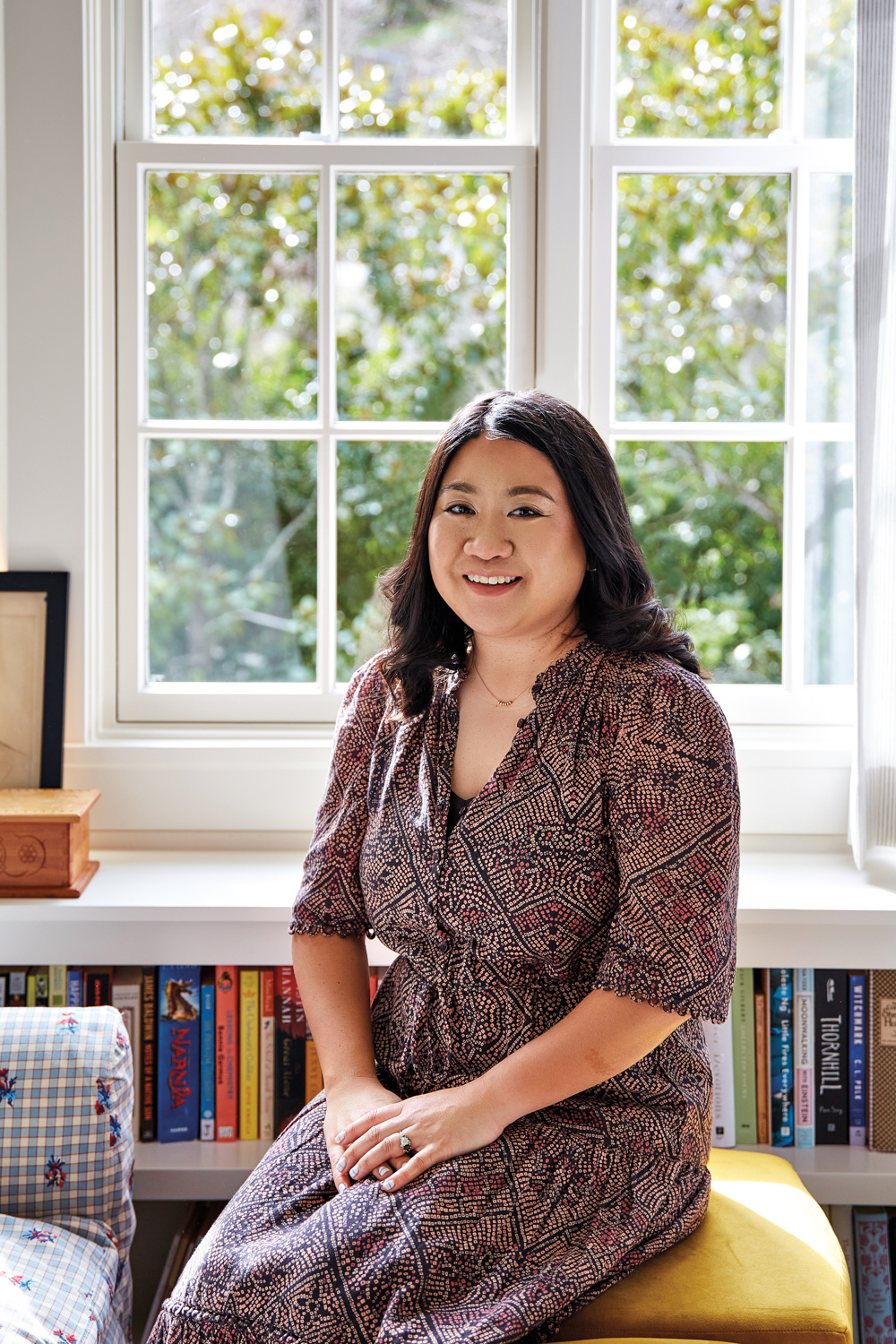 Portrait shot of designer Maria Wu set against a window and bookshelves