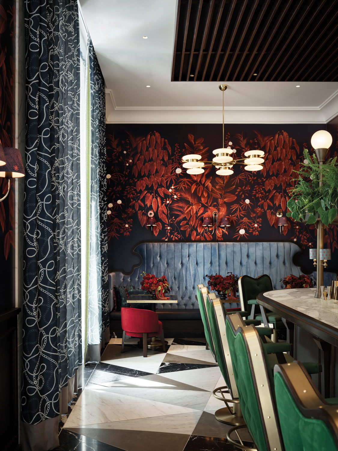 Holbrook House with bold red floral wallpaper, blue banquettes and green barstools