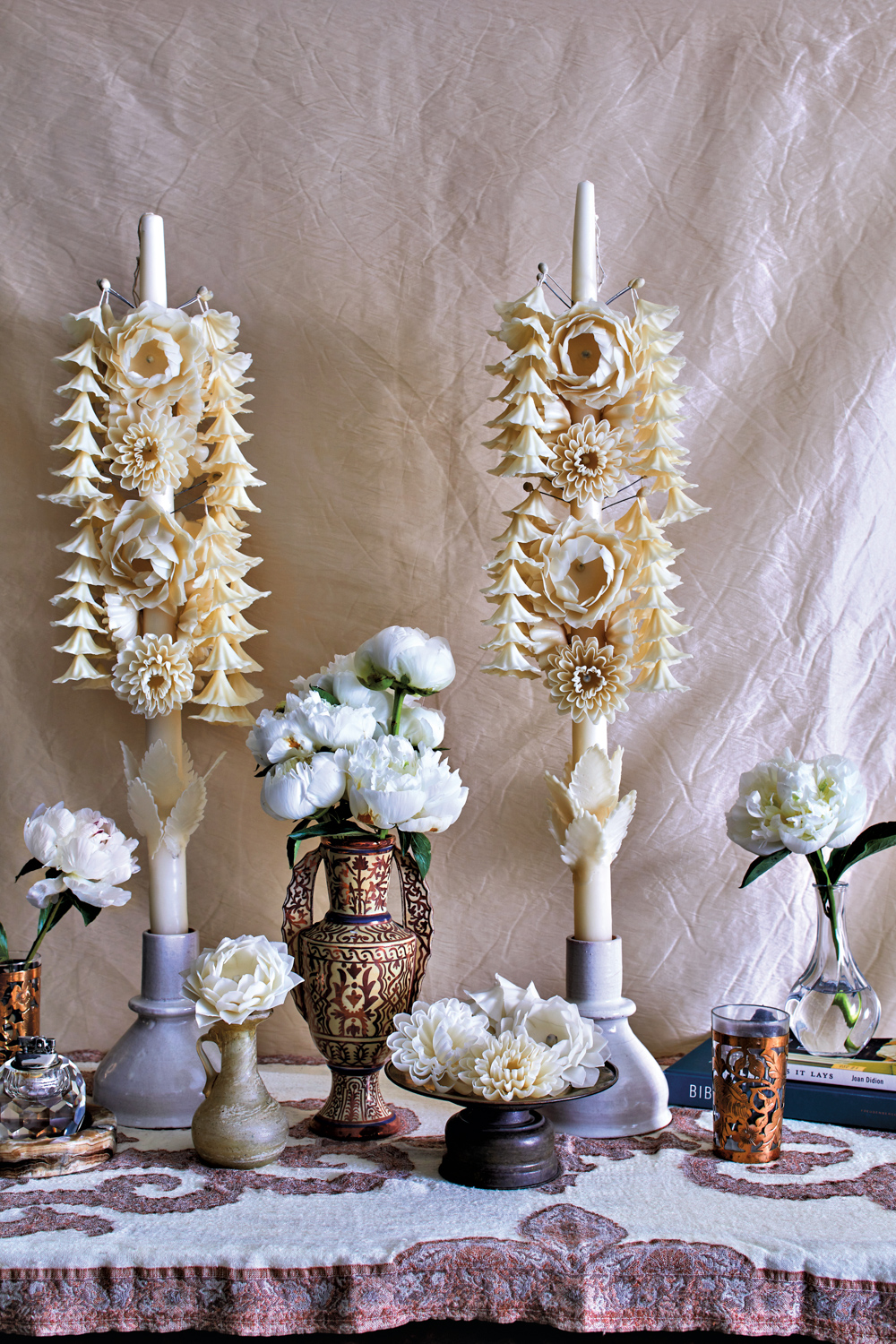 Candles sculpted into floral shapes from sun-bleached beeswax atop a tablescape by Zoë Gowen