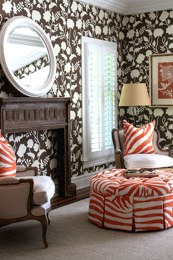 living room with brown floral wallpaper and red striped pillows
