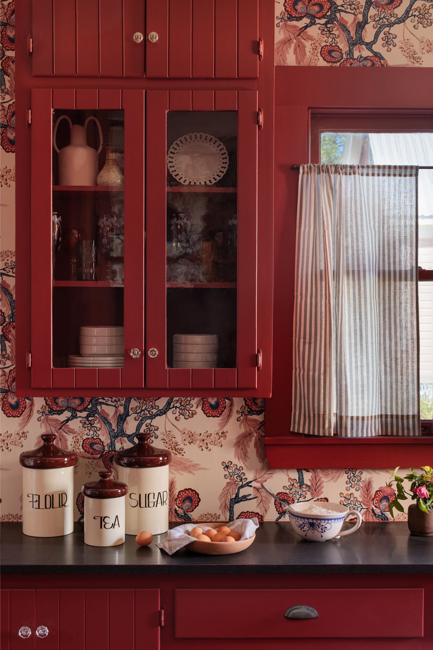 kitchen with crimson red cabinets and patterned wallpaper