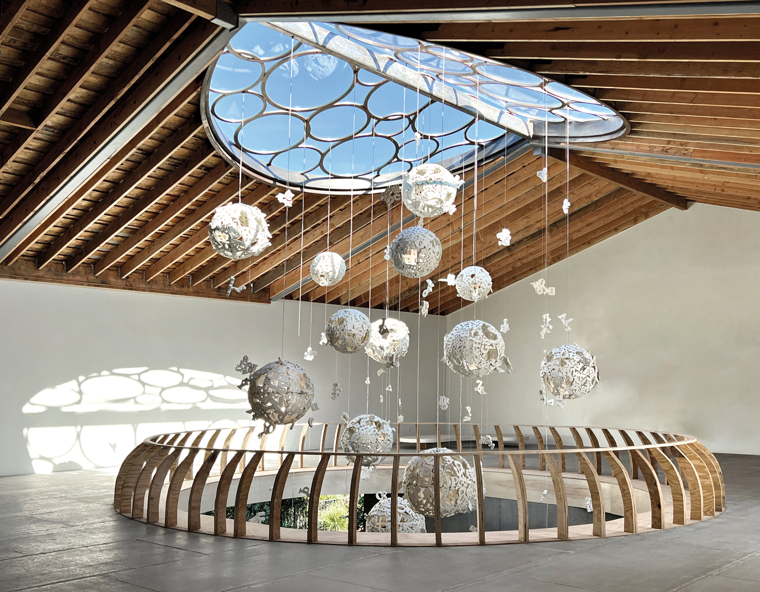 An art installation by Brigitte D’Annibale in which white spherical sculptures hang from an oculus in a barn-like building