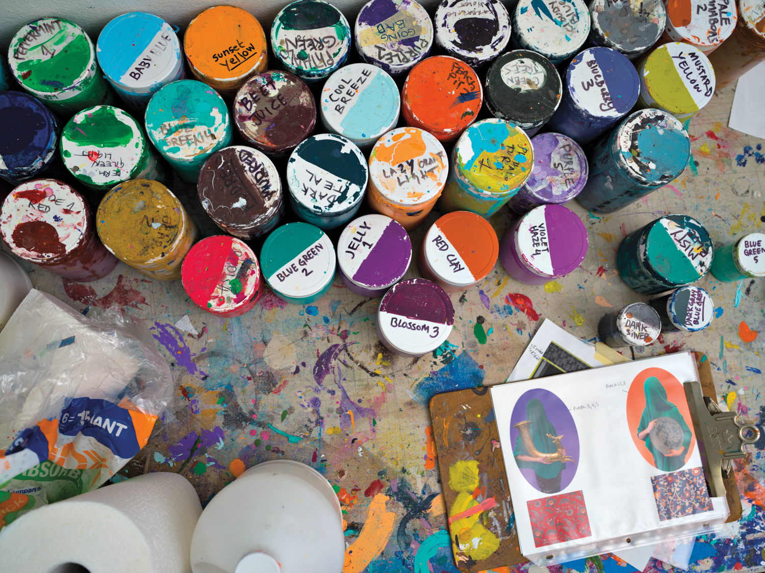 collection of acrylic paints in a variety of colors with handwritten labels against a paint splattered surface