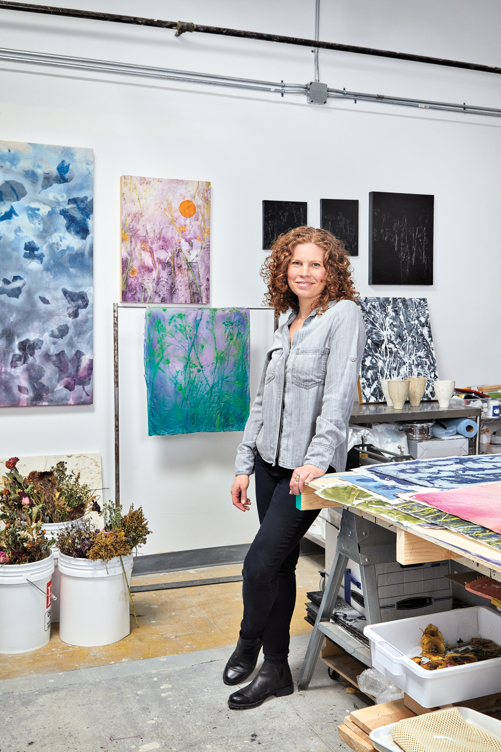 Jaclyn Mednicov standing in studio among floral paintings