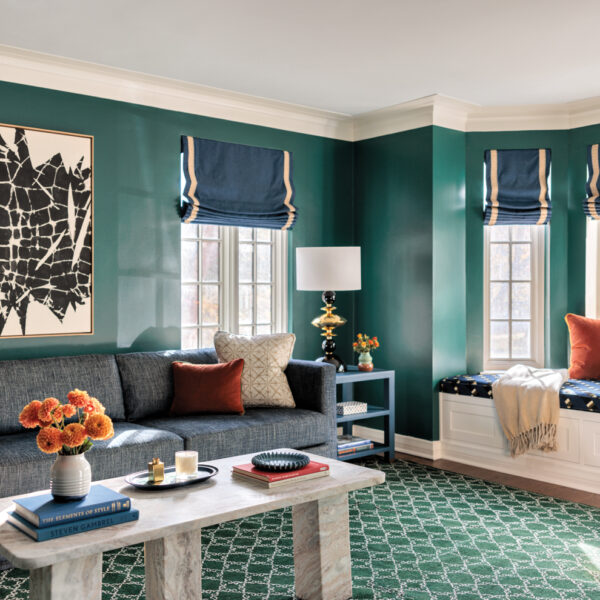 Living room with green walls, blue window treatments, green patterned carpeting, a couch, coffee table and window seat