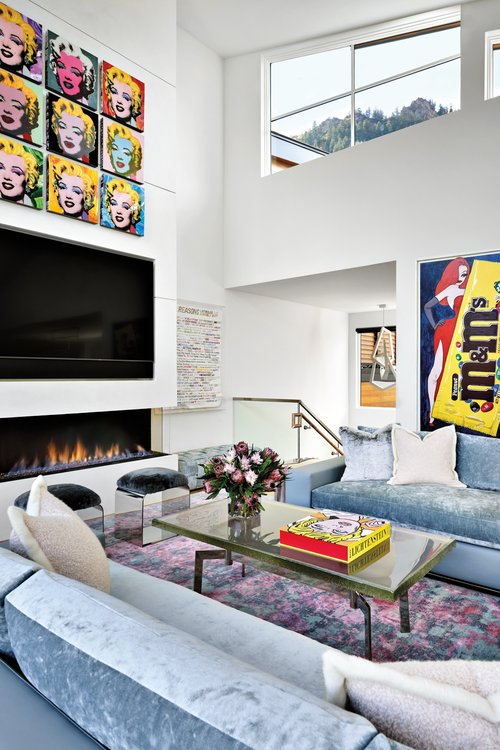 room with fireplace, colorful pop art, light blue sectional, wood coffee table and pink tone rug by Elizabeth Fields
