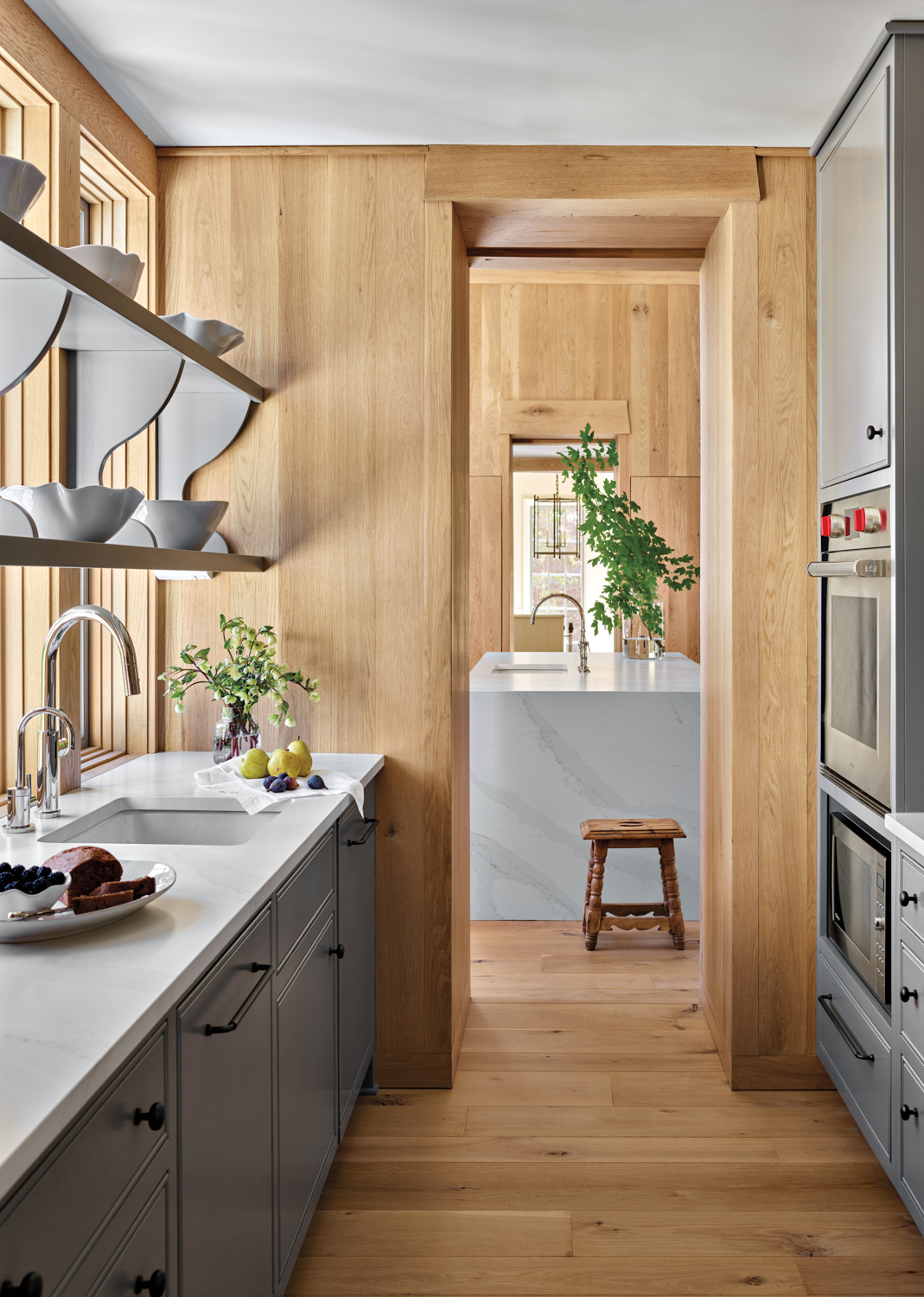 Wood-paneled pantry with gray-painted cabinetry...