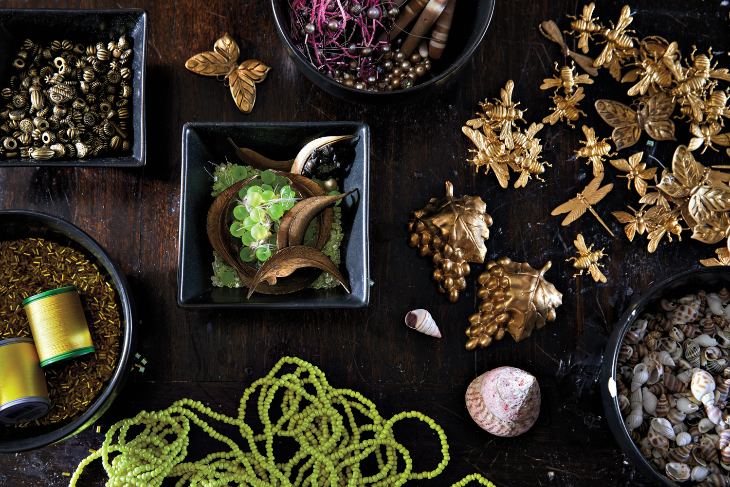 Dark wood tabletop with lime green, gold, brass and berry-colored beads