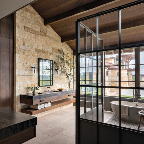 primary bathroom with stone walls and free-standing tub in home by Blair Burton