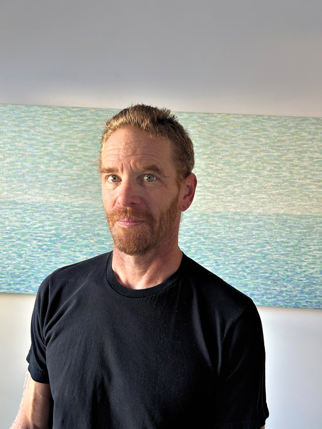 artist Kenneth Ober in front of one of his paintings