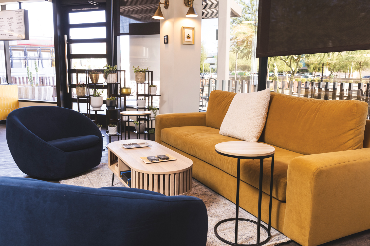 Restaurant seating area with mustard-colored sofa and navy arm chairs around a coffee table.