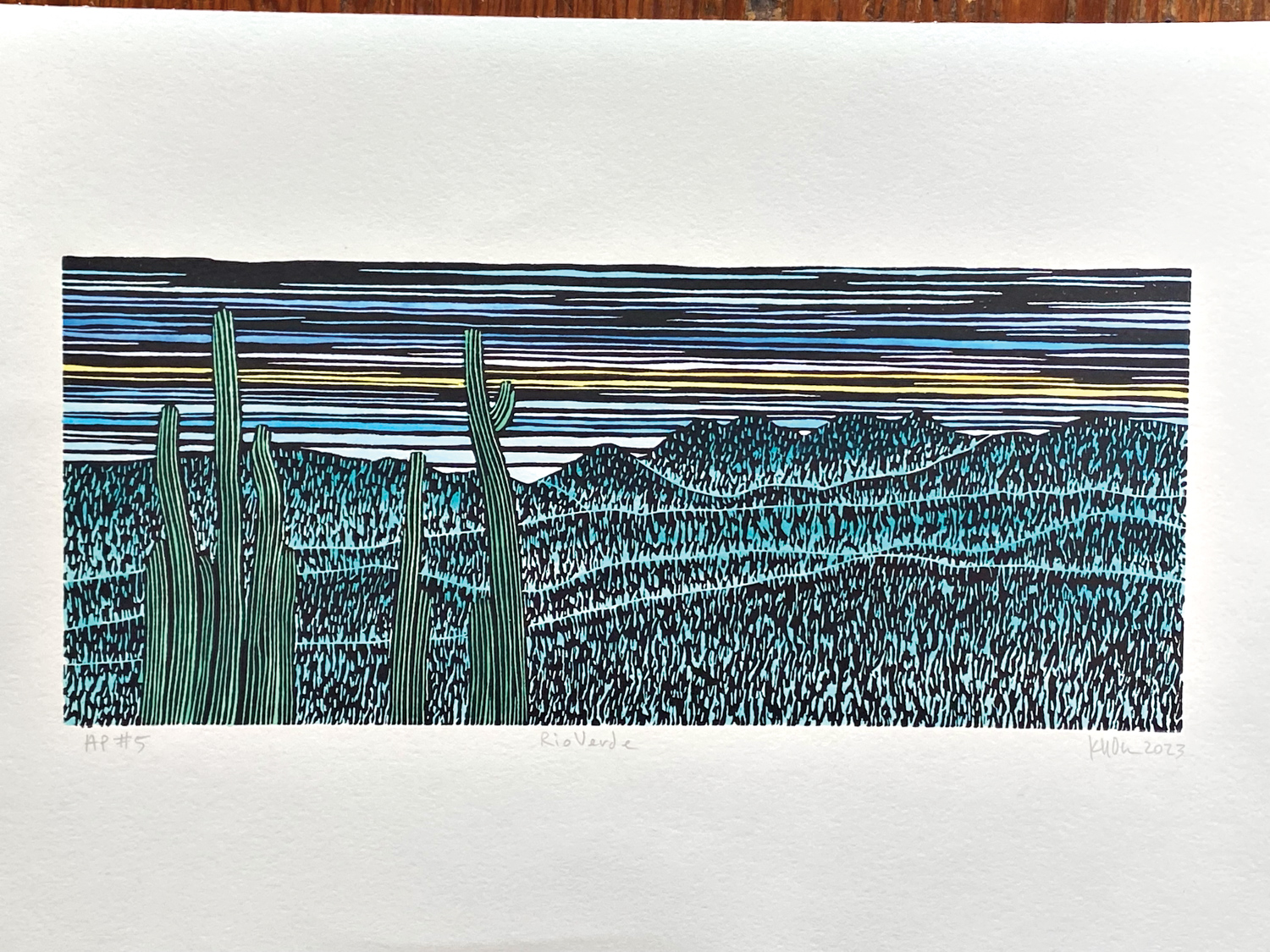 Linoleum block print depicting the desert landscape in blue and green hues