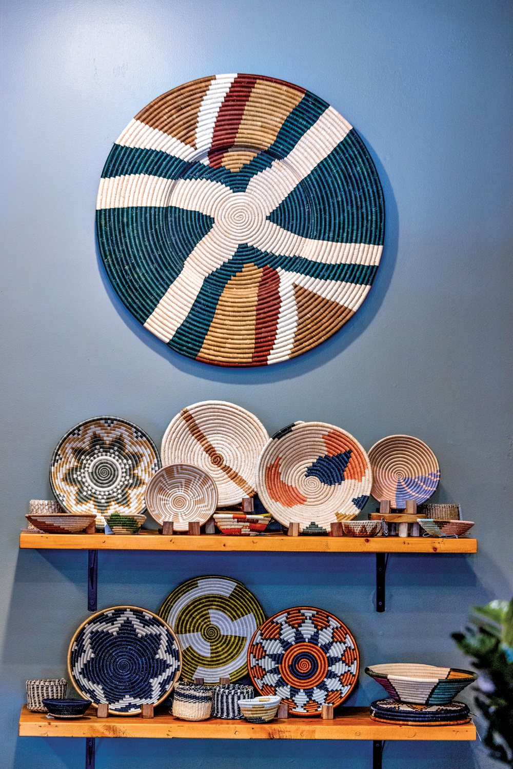 Multicolored coiled-rope bowls and dishes against a blue wall