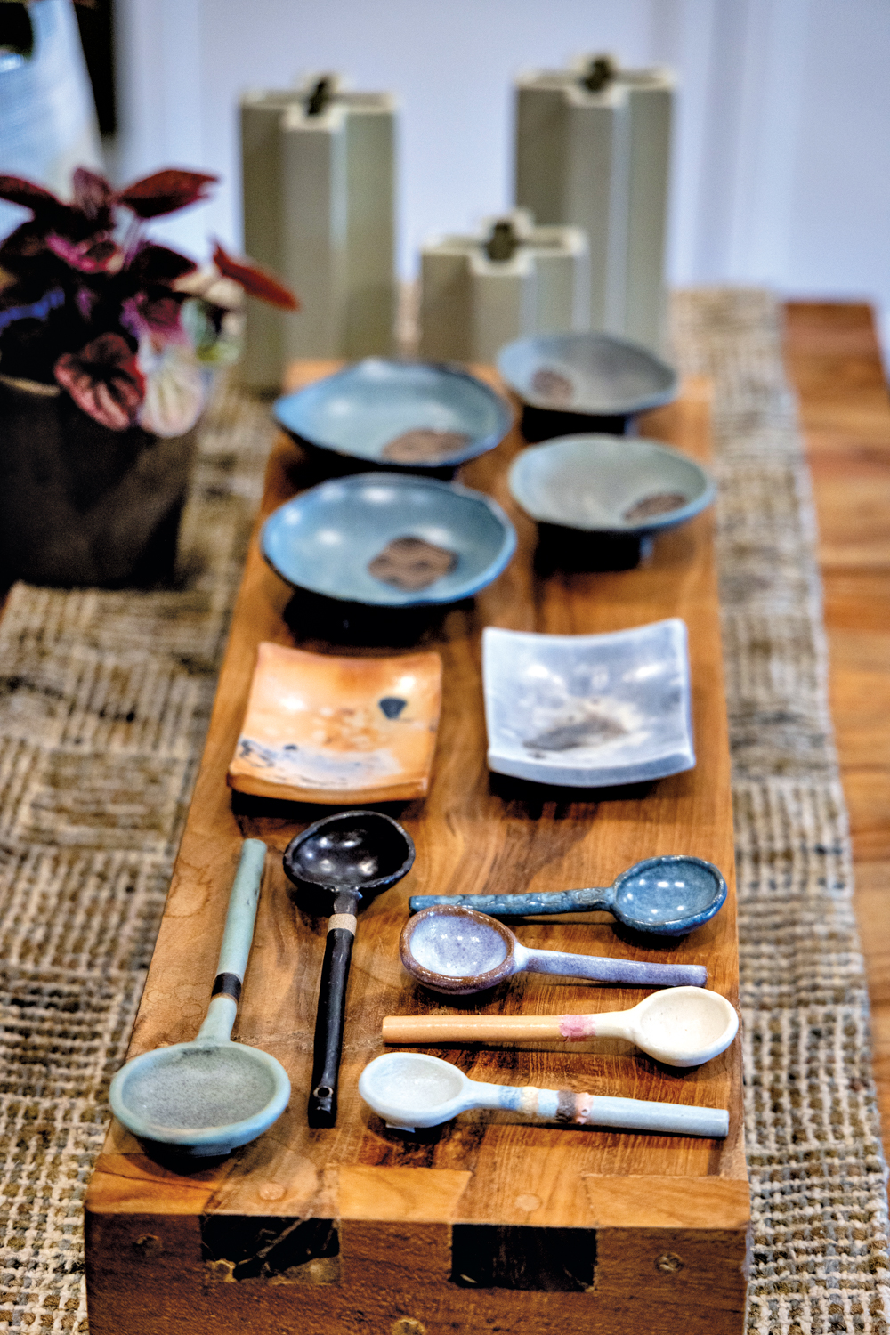 handmade ceramic dishes and spoons atop a wood plank