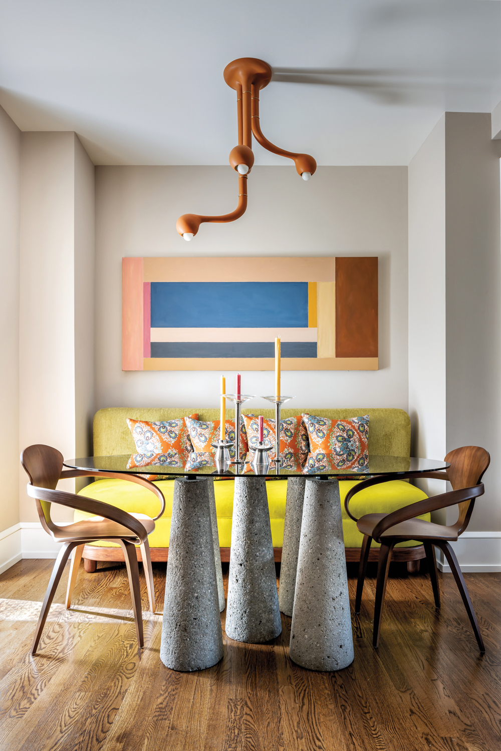 Sculptural lighting above a cement pillared dining table and chartreuse banquette seating