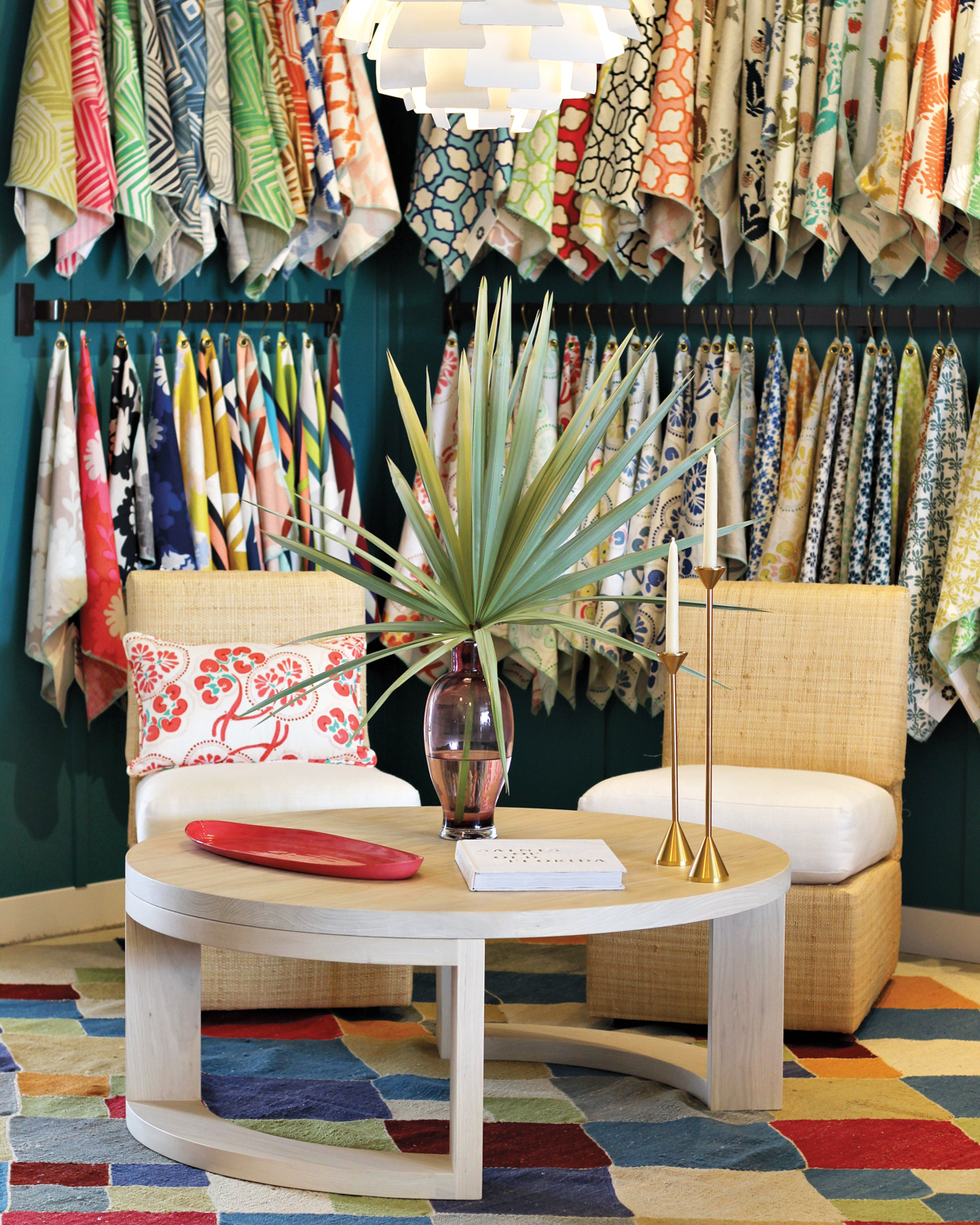 Wall of textile samples behind a small seating area atop a colorful rug