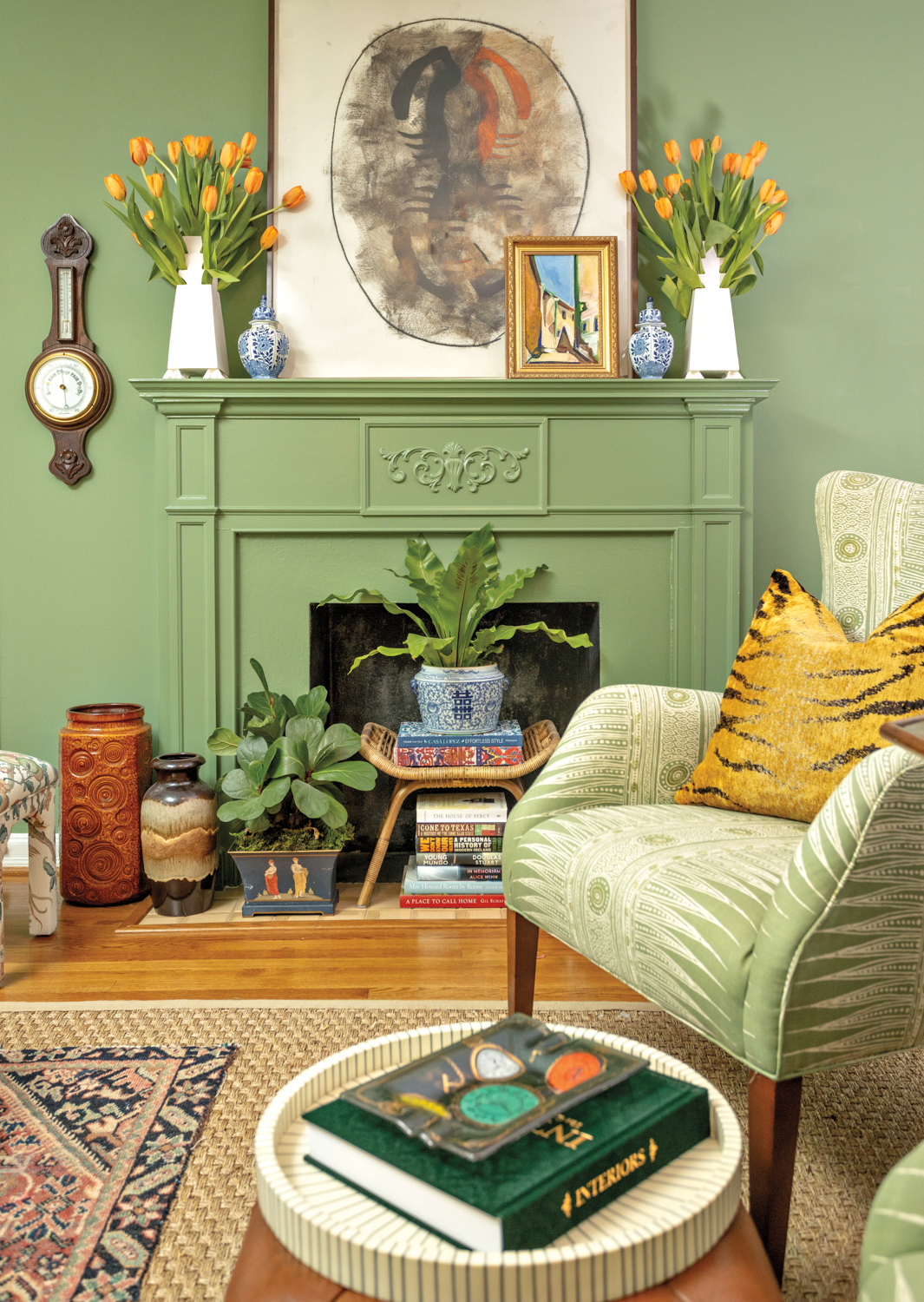Green paints the walls and the fireplace surround, a green armchair creates a vignette at Hunt & Bloom