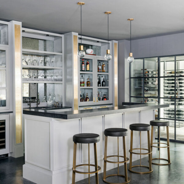 basement bar with white cabinets, four gold bar stools and gold pendant lighting. Construction Resources provided countertop fabrication and installation.
