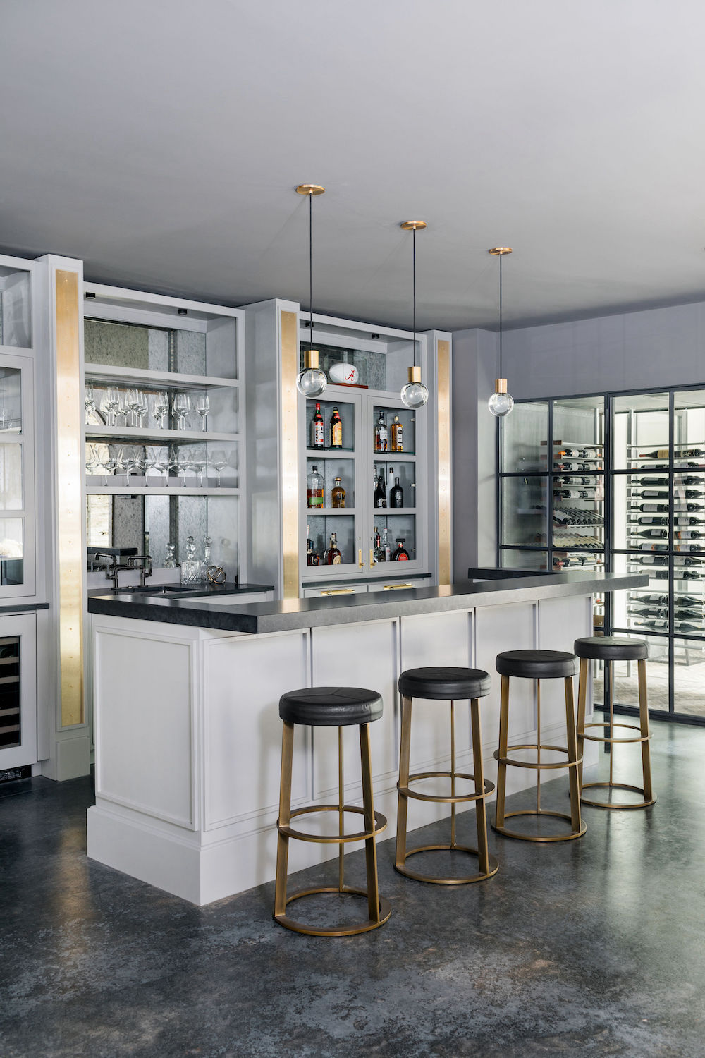 basement bar with white cabinets, four gold bar stools and gold pendant lighting. Construction Resources provided countertop fabrication and installation.