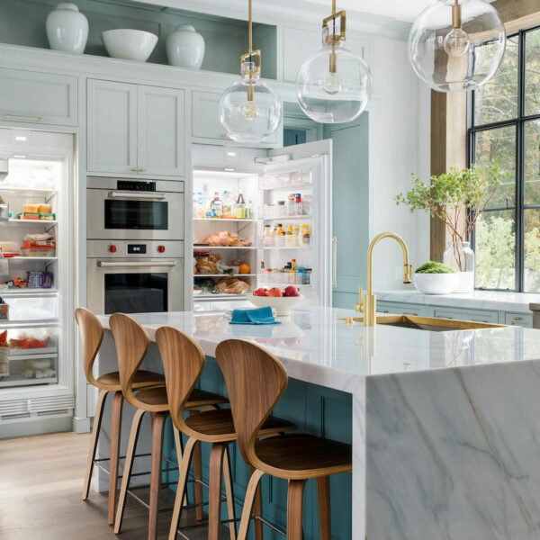 teal cabinets in contemporary kitchen with gold pendant lighting and four bar wood bar stools. Construction Resources provided countertop fabrication and installation.
