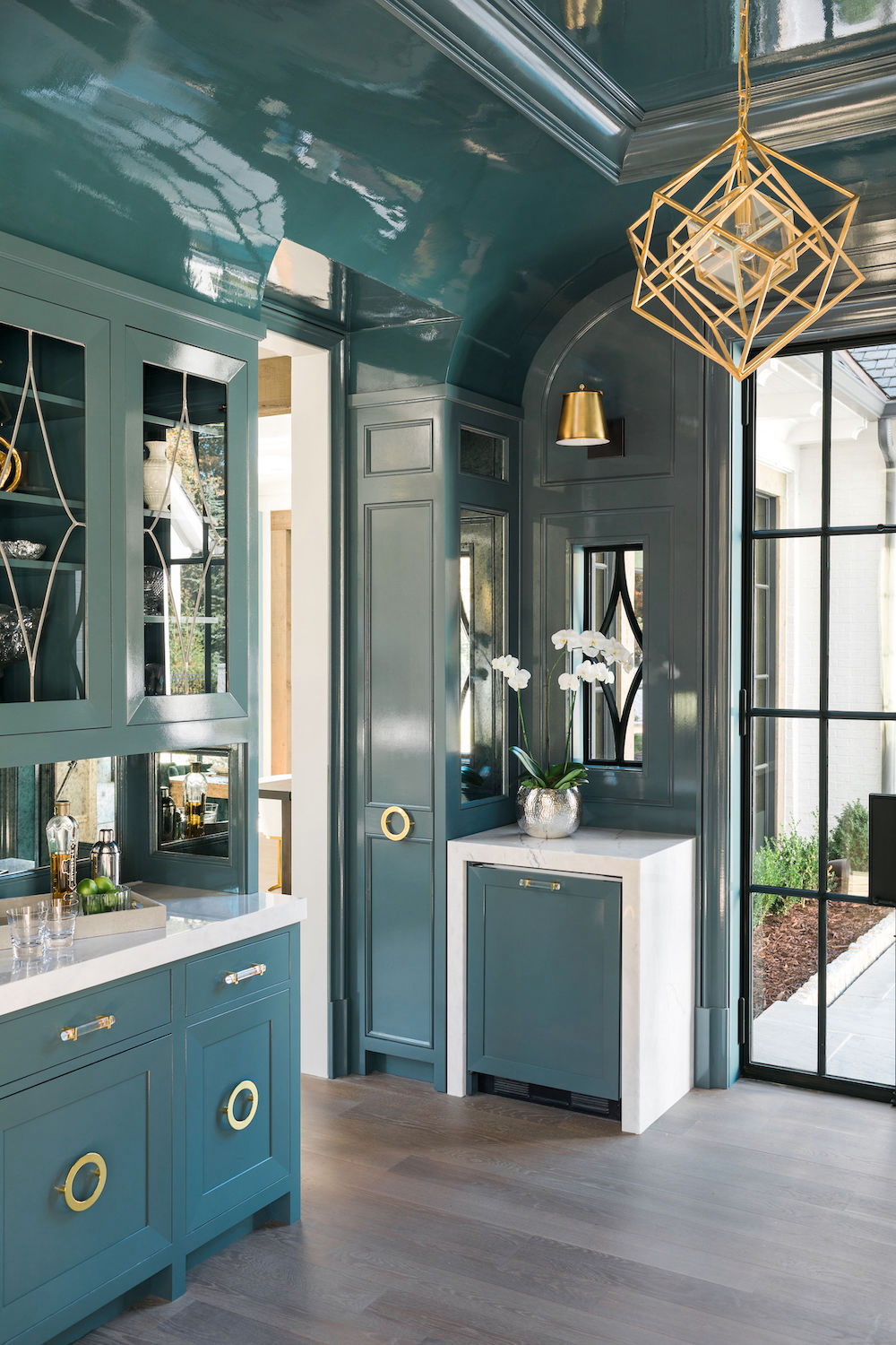 teal bar cabinets with white countertops and gold accents and lighting. Construction Resources provided countertop fabrication and installation.