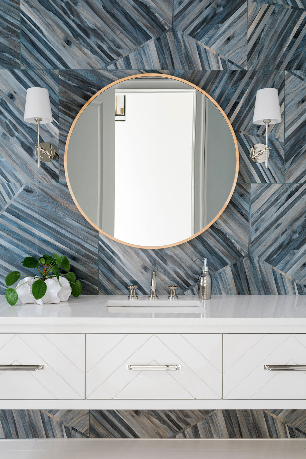 white floating cabinets in guest bedroom with silver hardware, faucets and lighting and blue tile backsplash. Construction Resources provided countertop fabrication and installation.
