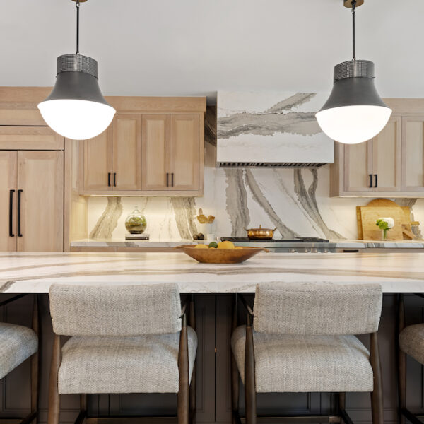 white kitchen with marble backsplash and light brown cabinets, silver pendant lighting