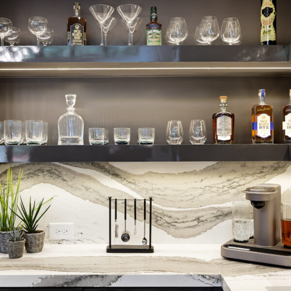 custom bar with marble countertops and open shelving to display glasses