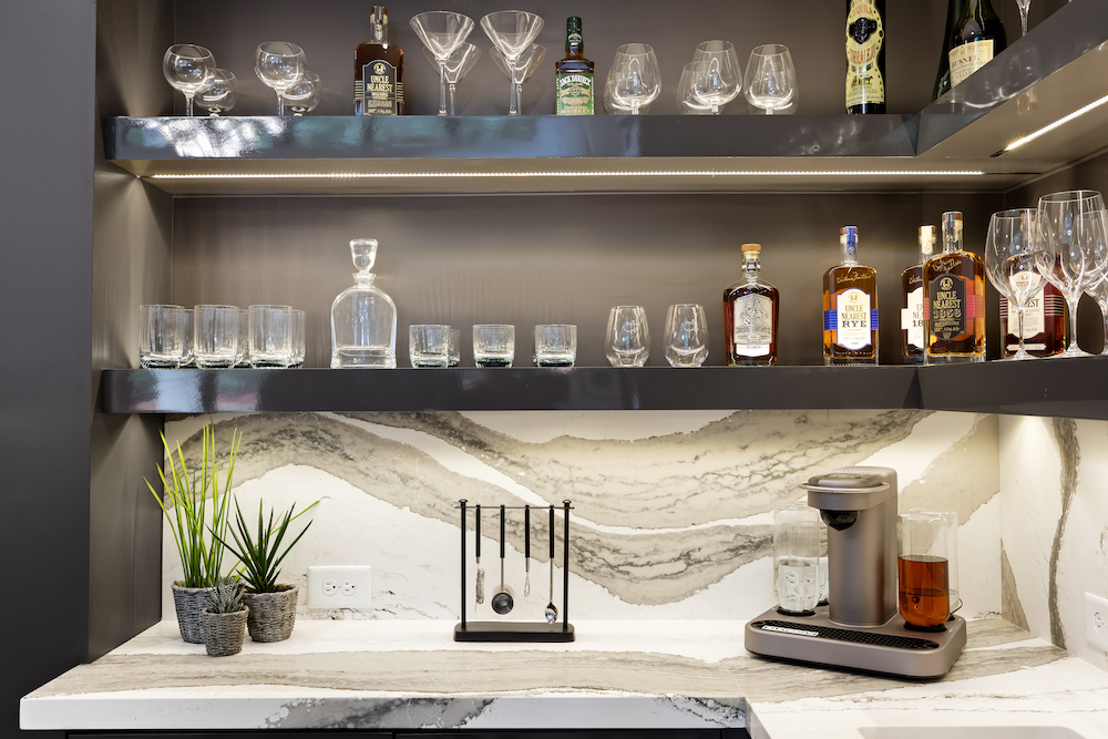custom bar with marble countertops and open shelving to display glasses