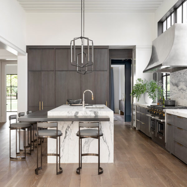 open kitchen with high ceilings, marble countertops and pendant lighting.