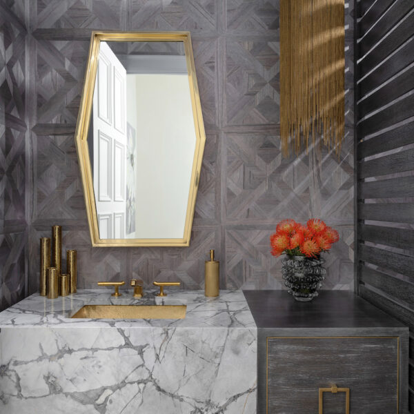guest bathroom with marble countertops, grey cabinets and gold sink and fixtures