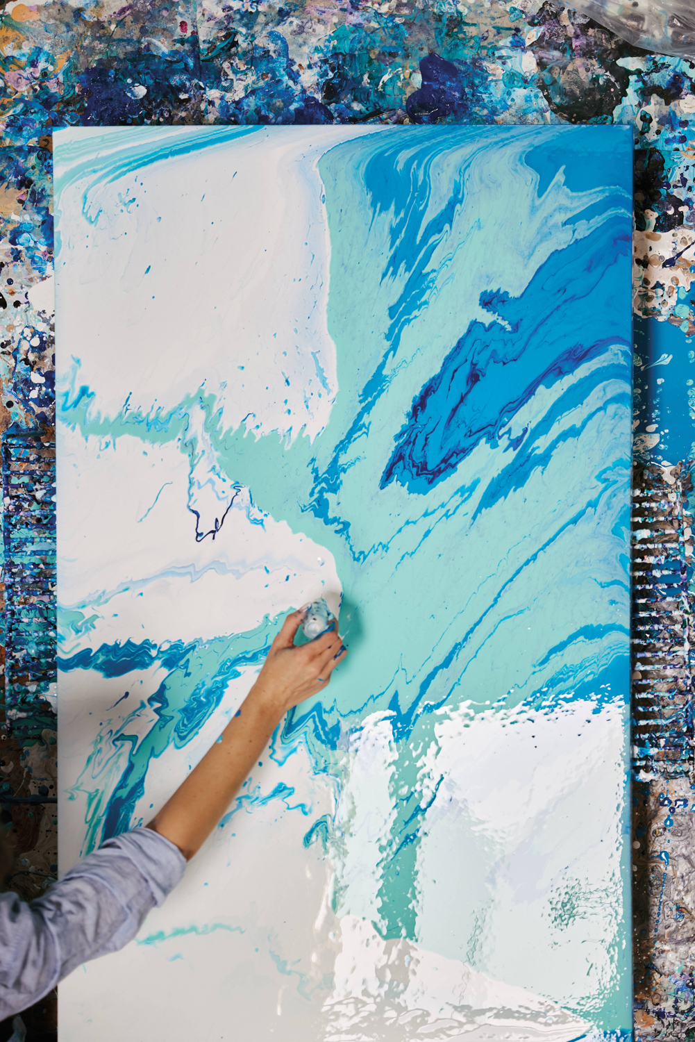 an artist adding white paint from a needle nose applicator to an abstract canvas