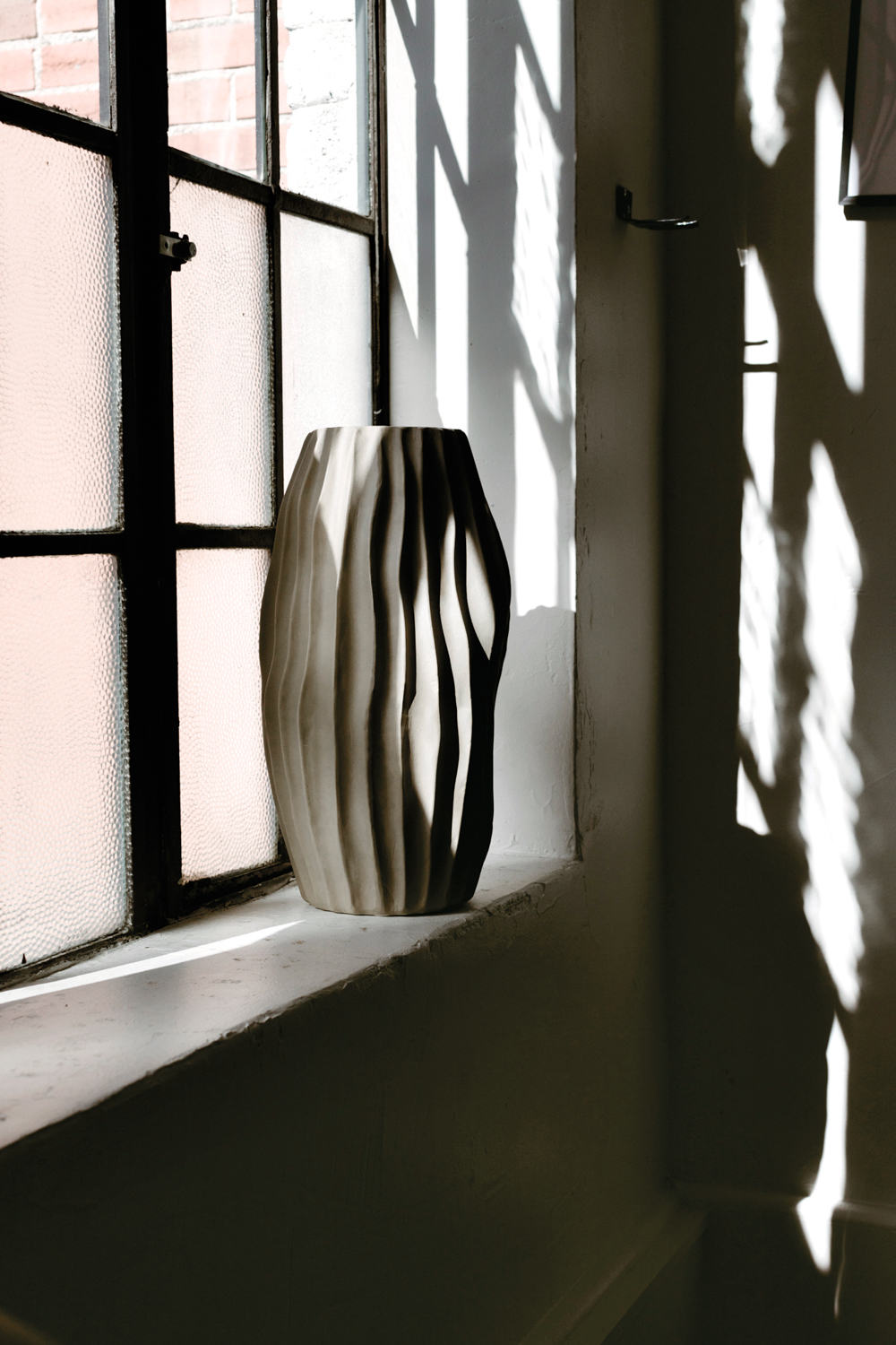 A textured ceramic vase on a windowsill.