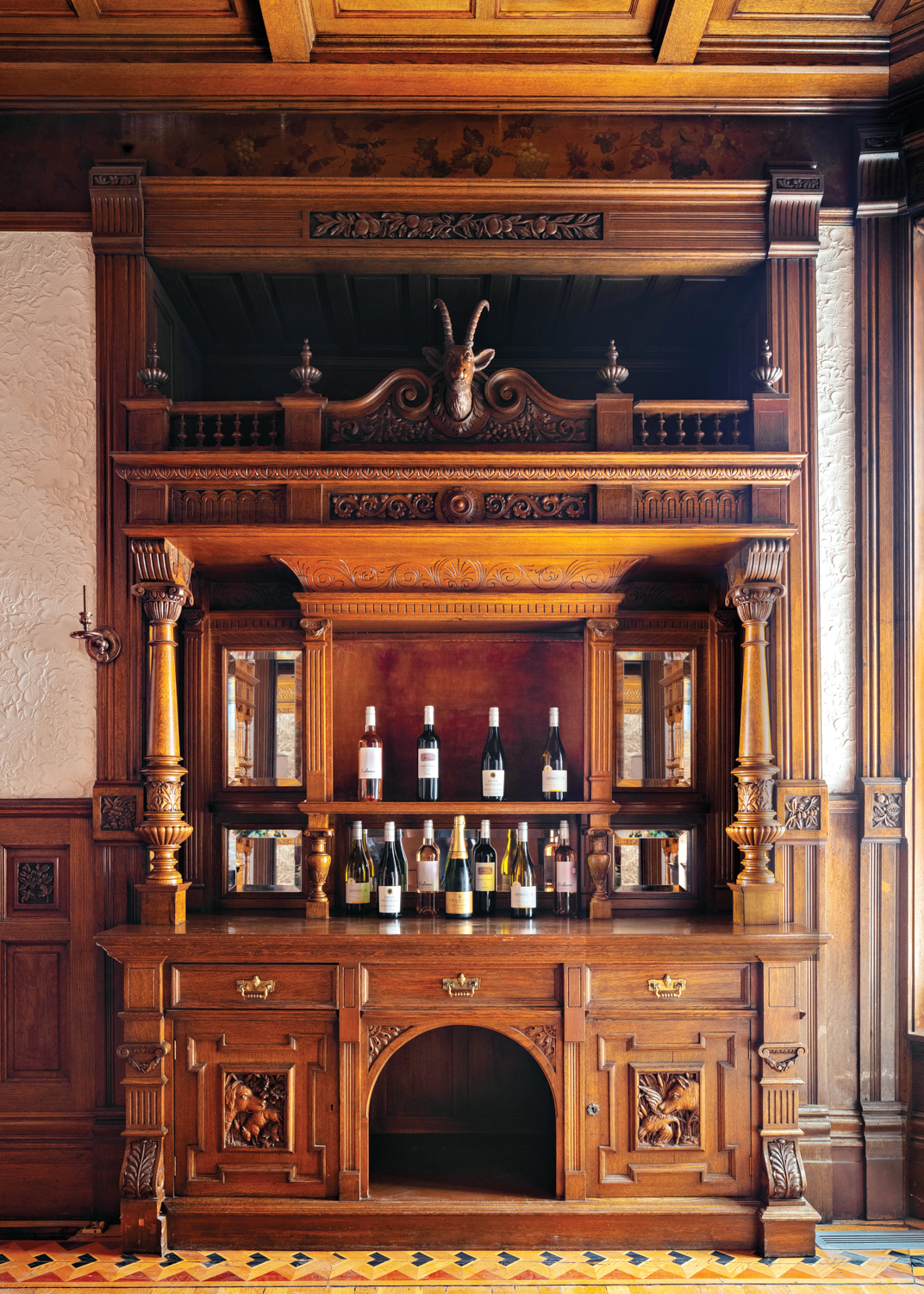 A 19th-century original carved-wood bar filled with liquor and wine bottles