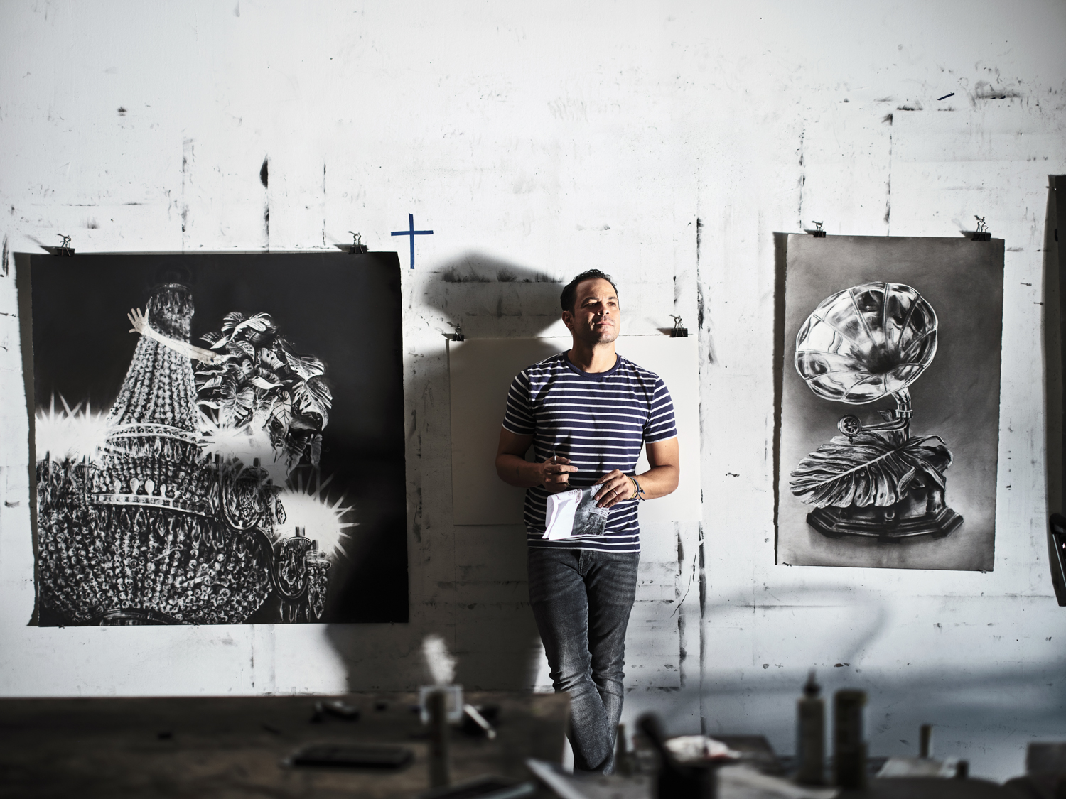 artist gonzalo fuenmayor standing against a wall in his studio with his artwork