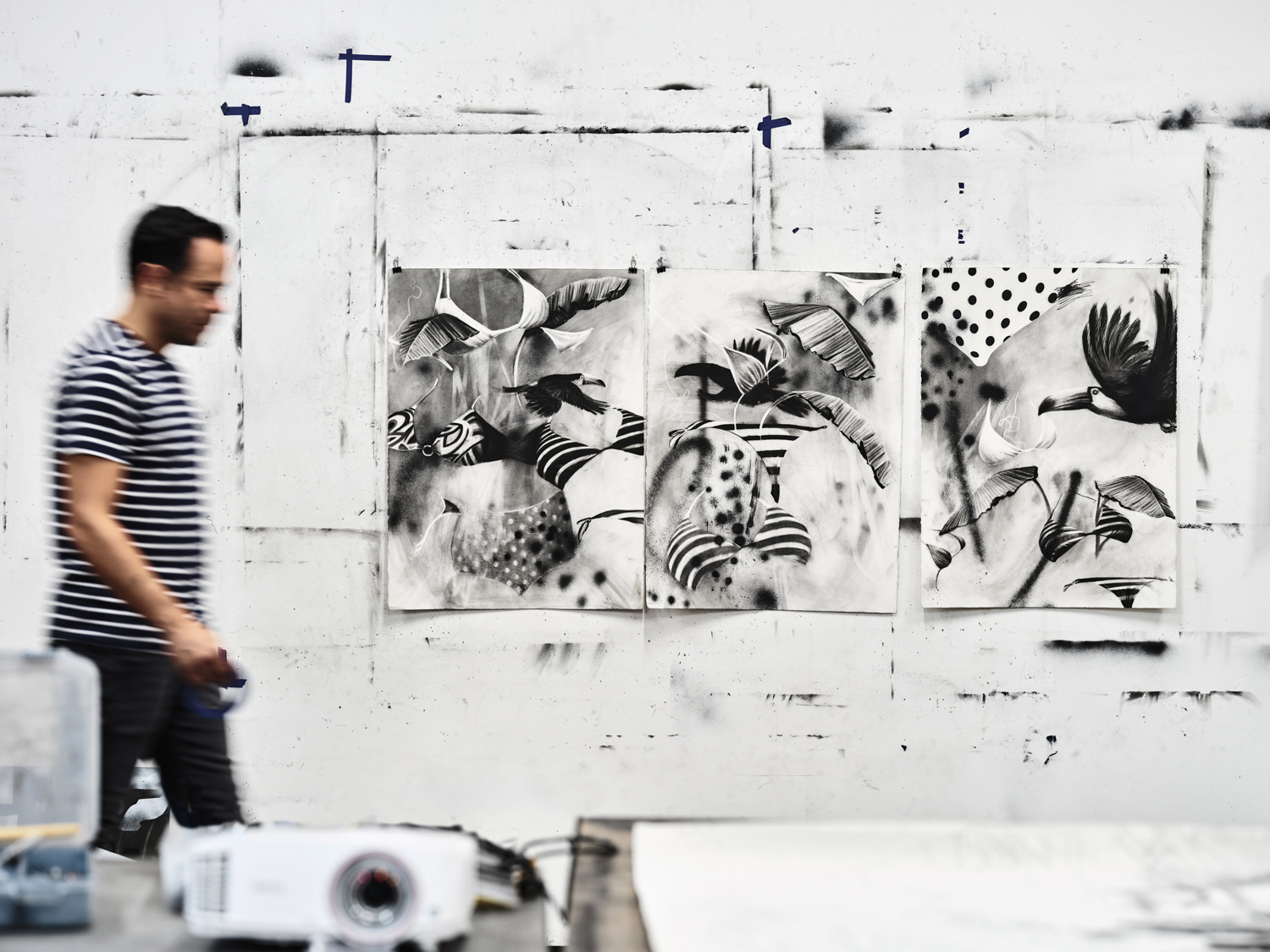 Artist gonzalo fuenmayor walking past his artwork in his studio