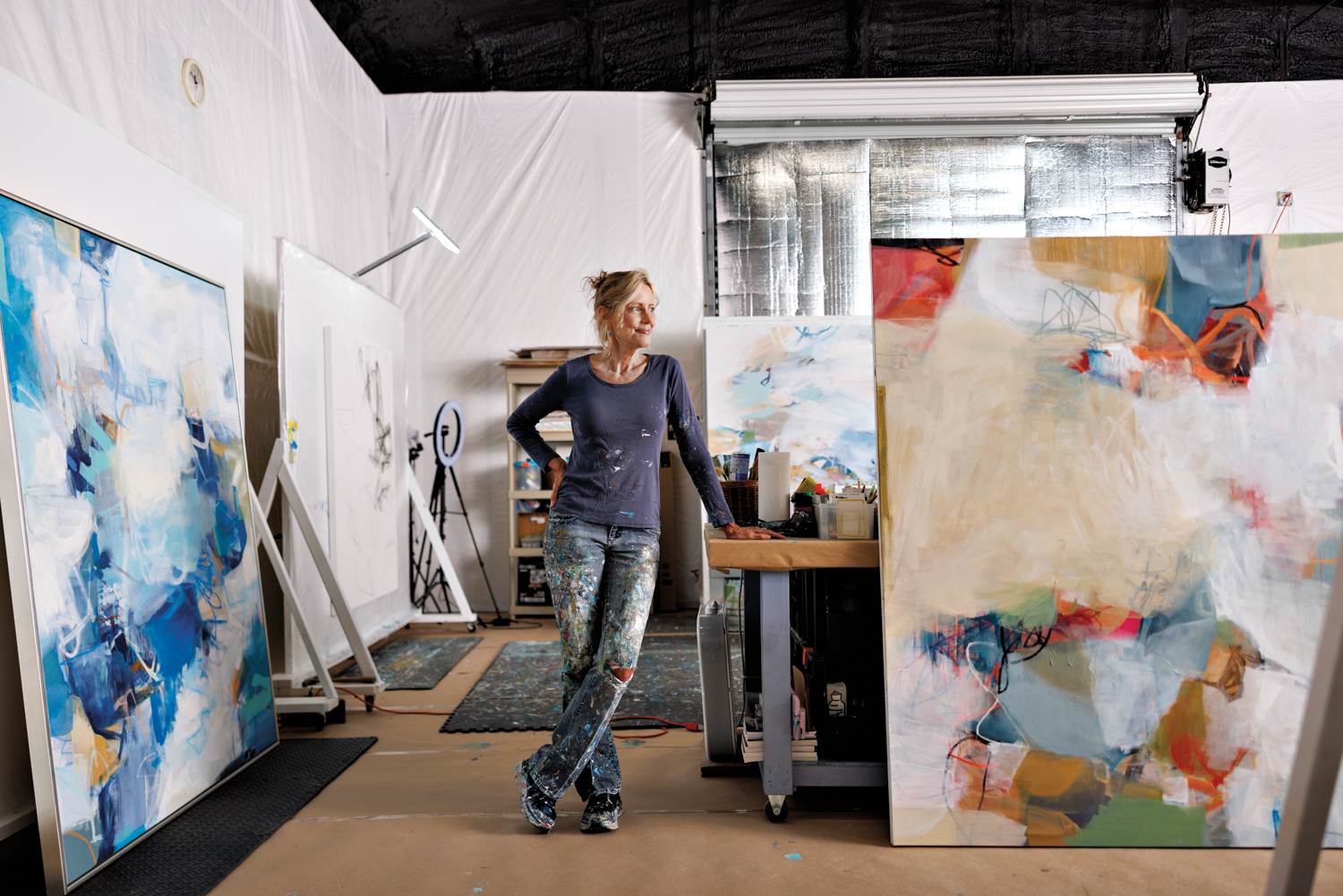 Artist Cat Tesla standing amid large-scale paintings in her studio