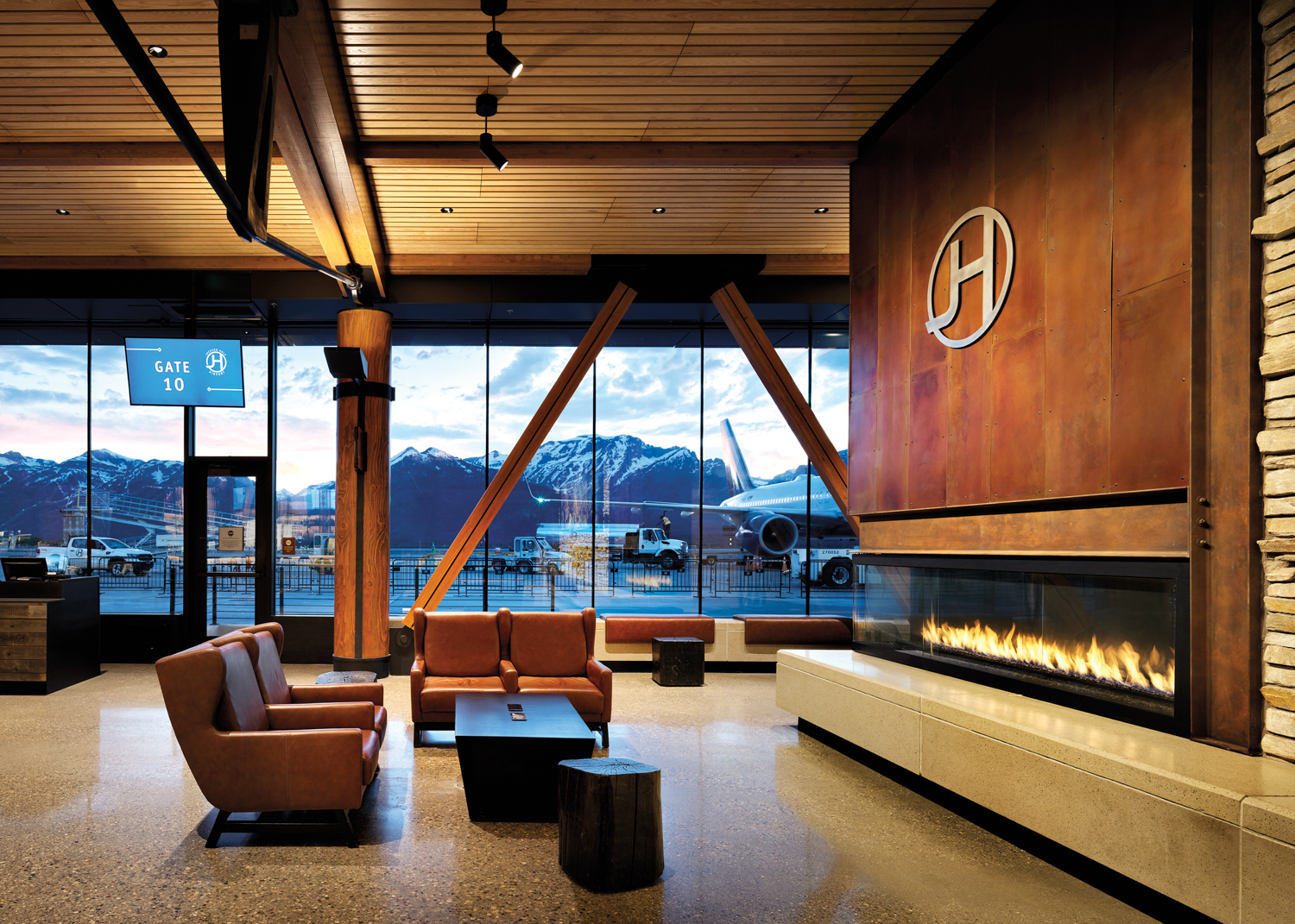 Jackson Hole Airport gate with leather armchairs facing a large fireplace set into a wall with metal panels